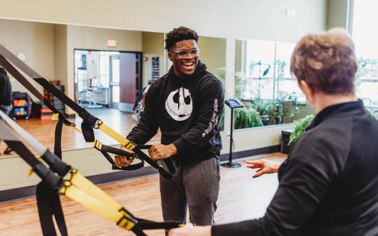 Photo of a student and instructor using work out equipment in the fitness center