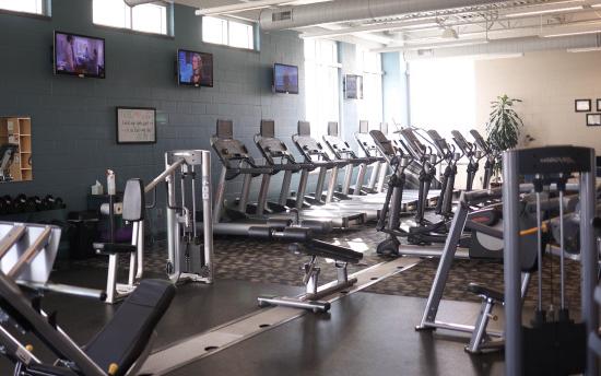 Photo of the fitness center showing several treadmills, weights and other pieces of workout equipment