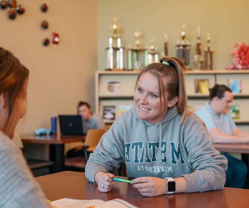 Two people sit at a table in an M State library